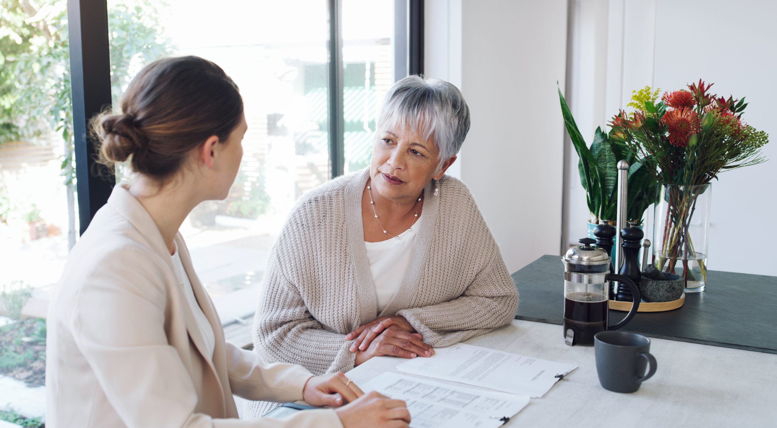 Shot of a senior woman meeting with a consultant to discuss paperwork at home